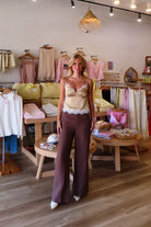 Brown, flowy linen pants with mid rise, zipper closure, wide leg, and natural textured fabric