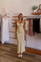 Yellow, satin maxi dress with V neckline, lace trim, open back, and adjustable cross straps