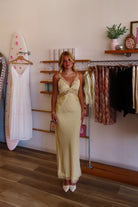 Yellow, satin maxi dress with V neckline, lace trim, open back, and adjustable cross straps