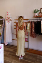 Yellow, satin maxi dress with V neckline, lace trim, open back, and adjustable cross straps