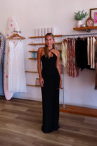Black, maxi dress with halter neckline, front cutout, fitted bodice, and draped scarf fabric