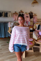 Pink, striped sweater with off shoulder neckline, oversized fit, and ribbed hem