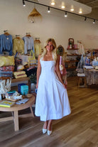 White, halter midi dress with square neckline, structured bodice, flared skirt, and side pockets | Pixelated Boutique, Virginia Beach Boutique, white maxi dress, white lace dress, boho maxi dress, bridal shower dress, bachelorette dress, graduation dress