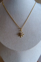Gold necklace with a star pendant on a mannequin bust.