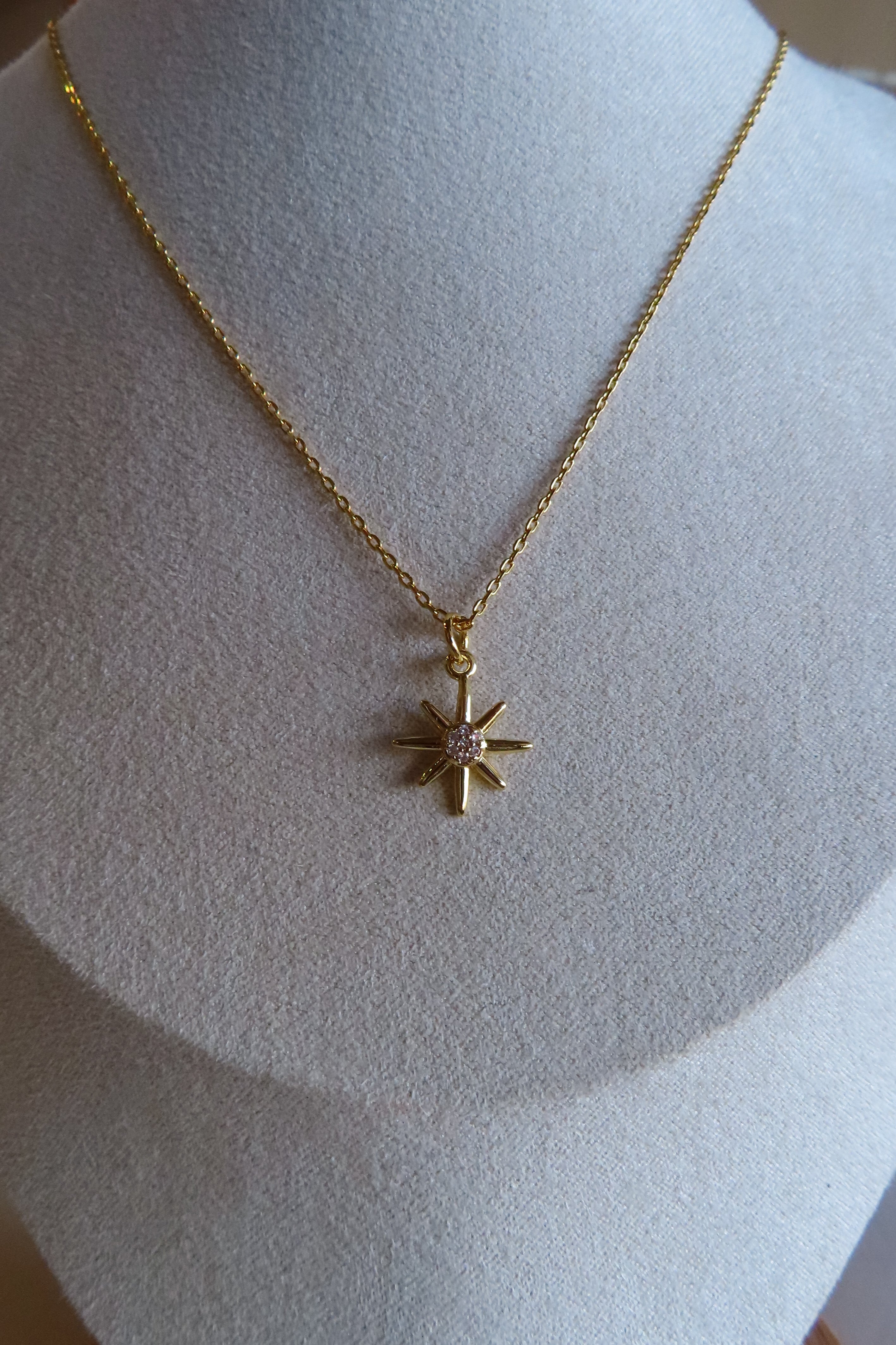 Gold necklace with a star pendant on a mannequin bust.