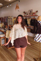 Cream, floral sequin poncho with boat neckline, asymmetrical hem, and sheer fabric | Pixelated Boutique, Virginia Beach Clothing Stores, Clothing Stores in Virginia Beach, Virginia Beach Boutique, 757 Boutique, Beach Fashion, Vacation Style, Coastal Cowgirl Aesthetic
