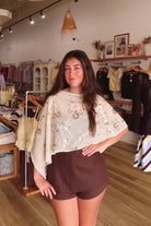Cream, floral sequin poncho with boat neckline, asymmetrical hem, and sheer fabric | Pixelated Boutique, Virginia Beach Clothing Stores, Clothing Stores in Virginia Beach, Virginia Beach Boutique, 757 Boutique, Beach Fashion, Vacation Style, Coastal Cowgirl Aesthetic
