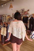 Cream, floral sequin poncho with boat neckline, asymmetrical hem, and sheer fabric | Pixelated Boutique, Virginia Beach Clothing Stores, Clothing Stores in Virginia Beach, Virginia Beach Boutique, 757 Boutique, Beach Fashion, Vacation Style, Coastal Cowgirl Aesthetic
