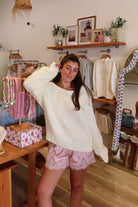 Cream, knit slightly oversized sweater with off-shoulder boat neckline and ribbed hem