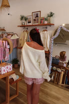 Cream, knit slightly oversized sweater with off-shoulder boat neckline and ribbed hem