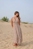 Tan and black, striped maxi dress with V neckline, halter tie, open back, and bubble hem | Pixelated Boutique, Women's Clothing, Boutique Clothing for Women, Women’s Formal Dress, Women’s Occasion Dress, Maxi Dress, Wedding Guest Dress, Prom Dress, Graduation Party Dress 