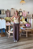 Brown, flowy linen pants with mid rise, zipper closure, wide leg, and natural textured fabric