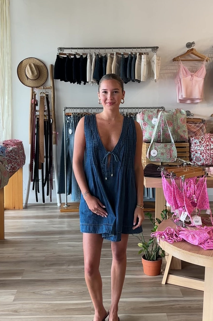 Blue, denim romper with V neckline, front tie, pockets, and pleated back, women’s boutique clothing, boutique clothing for women, coastal cowgirl outfits, coastal aesthetic clothing, business casual, concert outfit, 2000s fashion, western outfits