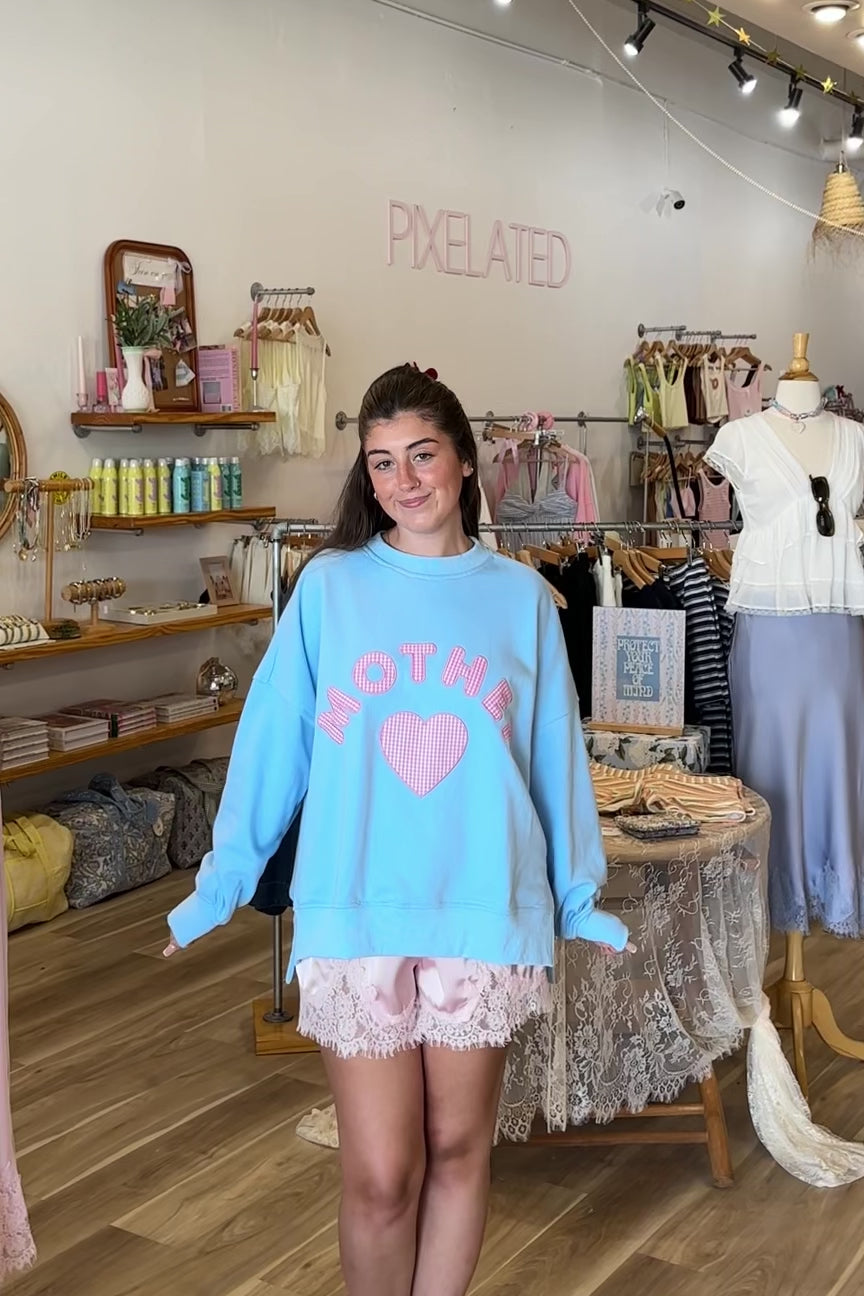 Blue, gingham heart and “MOTHER” embroidered in pink sweatshirt with crew neckline and fleece lining. Oversized and slightly cropped.

By The Beach Club